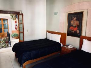 a bedroom with two beds and a painting on the wall at Hotel Santo Domingo in Zacatecas