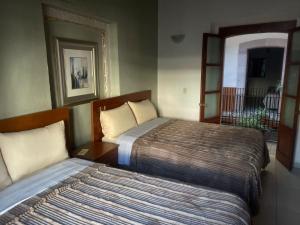 a hotel room with two beds and a balcony at Hotel Santo Domingo in Zacatecas