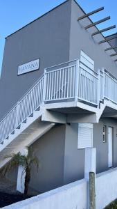 a white building with a staircase on the side of it at Havana Flats - Apto térreo 700m praia - Área Gourmet com 3 churrasqueiras in Balneário Gaivotas
