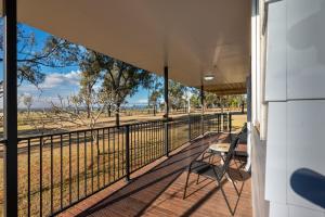a balcony with a table and chairs looking at a field at Clarendon Cottage, near Lowood , Fernvale, right on the BVRT in Clarendon