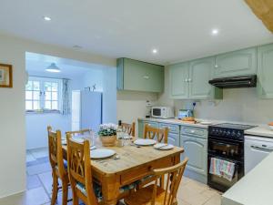 a kitchen with a wooden table with chairs and a refrigerator at 3 Bed in Dorchester oc-dc089 in Whitcombe