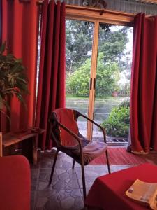 a chair in front of a window with red curtains at YayazNature Lodge in Grecia