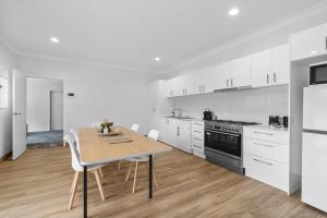 a kitchen with a wooden table and white cabinets at Misons Guesthouse in Mollymook