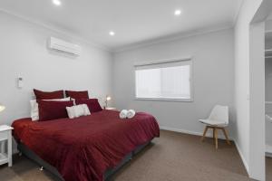 a bedroom with a bed with red sheets and a window at Misons Guesthouse in Mollymook