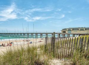 a beach with a pier and people in the water at Under the Oaks, A Downtown Hidden Gem in Wilmington
