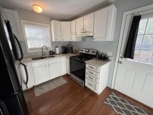 a kitchen with white cabinets and a black stove at Under the Oaks, A Downtown Hidden Gem in Wilmington +30 photos
