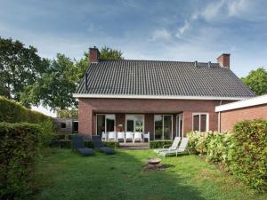 een stenen huis met witte stoelen en een patio bij Luxurious holiday home with wellness, in the middle of the North Brabant nature reserve near Leende in Leende