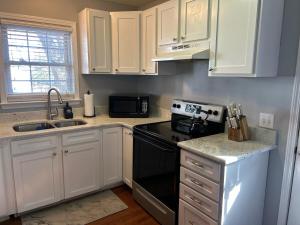 a kitchen with white cabinets and a black stove top oven at Under the Oaks, A Downtown Hidden Gem in Wilmington