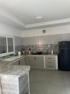 a kitchen with a black refrigerator and a counter at Les jardins de Sara in Mellita