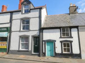 a white house with a blue door on a street at Chandlers Cottage in Conwy