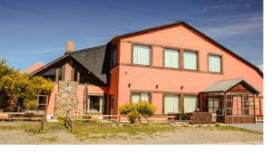 a large red brick building with a clock on it at Hotel Lunajuim in El Chalten