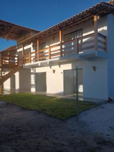 a house with a balcony and a lawn in front of it at Pousada Cristal - Caraiva in Porto Seguro