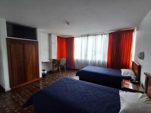 a hotel room with two beds and a desk at Hotel Rio Mayo in Pasto