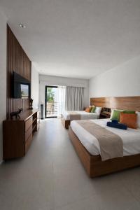 a large bedroom with two beds and a television at Aldea Thai Studios Steps to Beach and 5th Ave in Playa del Carmen +31 photos