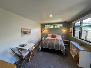 a bedroom with a bed and a desk and a window at East Rock - Cosy Guesthouse in Kelvin Heights in Queenstown