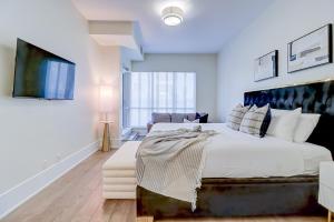 a white bedroom with a large bed and a couch at Skyline Penthouse in Toronto