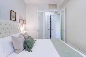 a white bedroom with a large white bed with pillows at Skyline Penthouse in Toronto