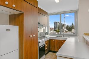 a kitchen with wooden cabinets and a large window at Kirra Gardens Unit 9 in Gold Coast