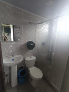 a bathroom with a toilet and a sink and a shower at Hotel Puerto azul in Chitaraque