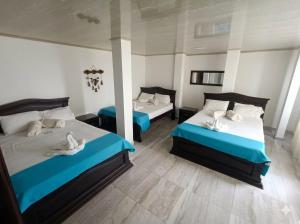 a bedroom with two beds with blue and white sheets at Hotel Puerto azul in Chitaraque