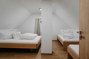 two beds in a room with white walls and wood floors at Designové chalupy v Jeseníkách - Přemyslovské stráně in Kociánov