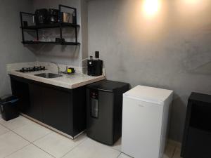 a kitchen with a sink and a small refrigerator at Flat Palmas Vivence Suítes in Palmas