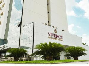 a white building with palm trees in front of it at Flat Palmas Vivence Suítes in Palmas