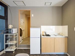 a kitchen with a white refrigerator in a room at Retrospect Stay Kannai in Yokohama