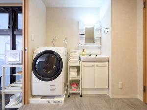 a laundry room with a washing machine and a sink at Retrospect Stay Kannai in Yokohama