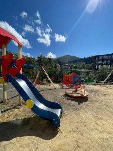 a playground with a blue and red slide and swings at Orbi Palace Bakuriani in Bakuriani