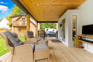 a screened porch with wicker chairs and a television at Spruce Suite Historic NOTL - VINEYARD RETREAT in Niagara-on-the-Lake