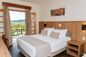 a bedroom with a large white bed and a balcony at Hotel Monreale Resort in Poços de Caldas +125 photos