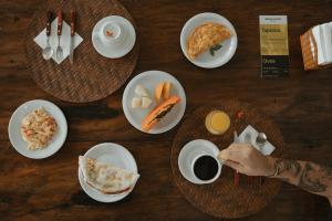 a table with plates of food and a person drinking coffee at Pousada Erva Doce in Arraial d'Ajuda +56 photos