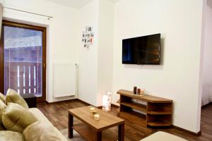 a living room with a couch and a tv on a wall at Apartmán Chopok juh Monika in Tale