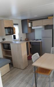 a kitchen with wooden cabinets and a table and chairs at Monpetitmobilhome in Ascarat