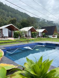 a resort with a swimming pool and some houses at Surya Camp Buahan in Kubupenlokan