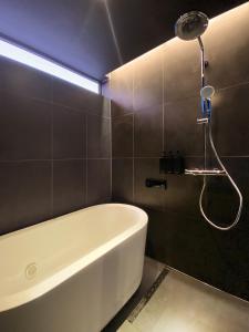 a bathroom with a white tub and a shower at Kuro Hakuba in Hakuba