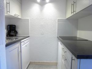 メリベルにあるAttractive Apartment in M ribel near Les 3 Vall esのキッチン(白いキャビネット、カウンタートップ付)