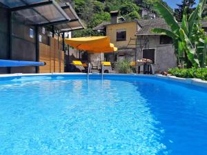 a large blue swimming pool with an umbrella at Rosato in Gravedona