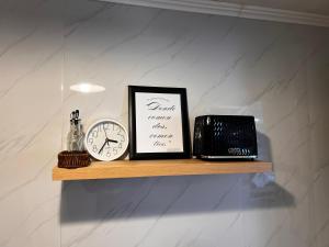 a shelf with a clock and a picture and a laptop at Magnolia Mini House Casa A in Puerto Natales
