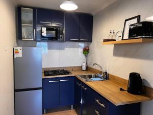 a kitchen with blue cabinets and a white refrigerator at Magnolia Mini House Casa A in Puerto Natales