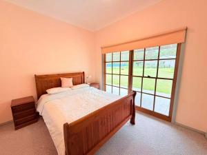 a bedroom with a bed and a large window at Spacious Queen and Single Farmhouse Room in Worragee
