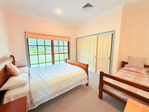 a bedroom with a bed and a bench and a window at Spacious Queen and Single Farmhouse Room in Worragee +39 photos