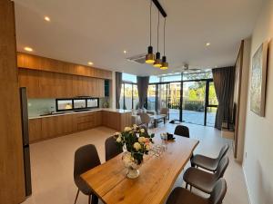 a dining room and kitchen with a wooden table and chairs at Aurora Golf Villa in Bình Sum