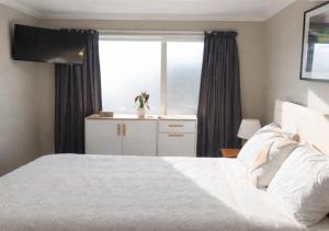 a bedroom with a white bed and a window at Stylish Tawa Retreat in Wellington