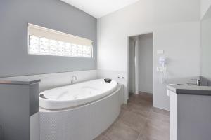 a white bathroom with a tub and a sink at Waves Luxury Suites & Port Central Apartments in Port Campbell