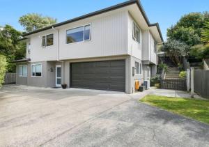 a large white house with a garage at Stylish Tawa Retreat in Wellington