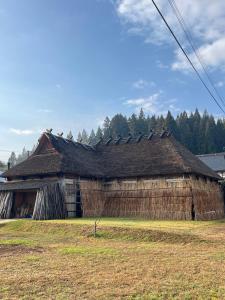 an old building with a roof on a field at うご八かやぶ㐂 in Narazaki