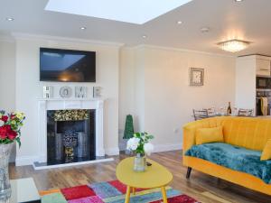a living room with a yellow couch and a fireplace at Ailsa Craig View in Stranraer