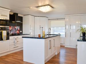 a kitchen with white cabinets and a black counter top at Ailsa Craig View in Stranraer